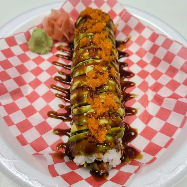 Dragon sushi roll with avocado, eel sauce, and orange tobiko, served with wasabi and ginger.