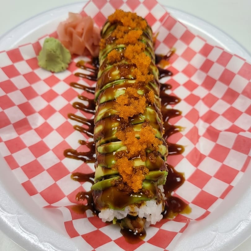 Dragon sushi roll with avocado, eel sauce, and orange tobiko, served with wasabi and ginger.